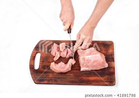 Cutting raw meat with a kitchen knife on a cutting board isolated on white background 41891798