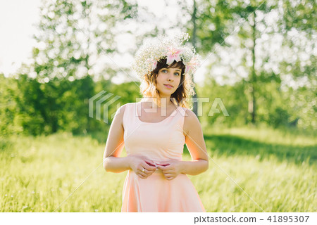 beautiful girl with a wreath of flowers on her head smiling outdoors on a Sunny day 41895307