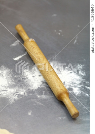 a wooden rolling-pin on a steel table top a wooden rolling-pin on a steel table top 41896649