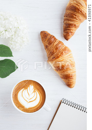 Cappuccino, two croissants and notebook. 41898971