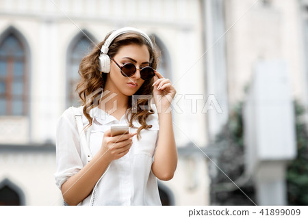 young woman listening to music on headphones 41899009