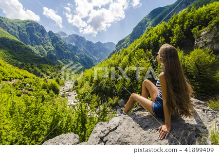 Woman sitting on a rock and looking at mountains Woman sitting on a rock and looking at mountains 41899409