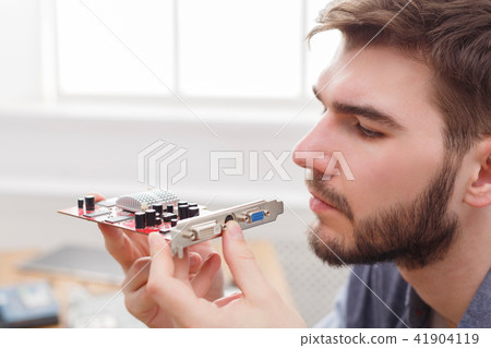 Programmer studying broken video card in workshop Programmer studying broken video card in workshop 41904119