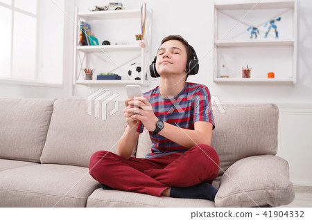 Teenage boy enjoying music in headphones at home Teenage boy enjoying music in headphones at home 41904332