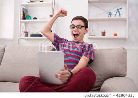 Teenage boy using digital tablet on sofa at home Teenage boy using digital tablet on sofa at home 41904335