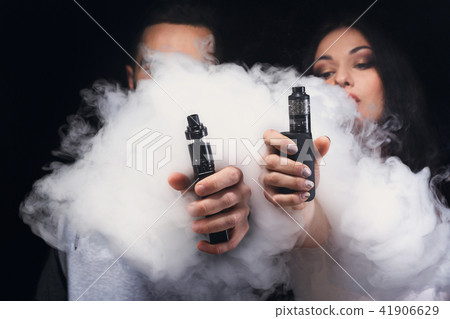 Young couple vaping e cigarette with smoke on Stock Photo