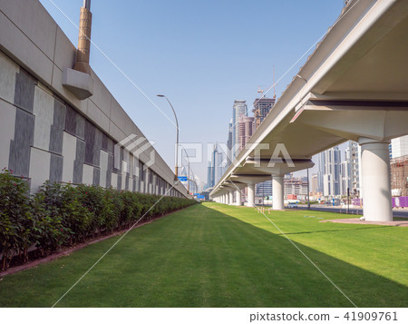 A green flowerbed with grass next to the road on Dubai Street. 41909761