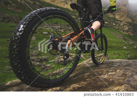 Legs of bicyclist and rear wheel close-up view of back mtb bike in mountains against background of 41910863