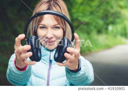 Happy girl outdoors in forest holds headphones. The concept of stereo music anywhere. Walking Music 41910901