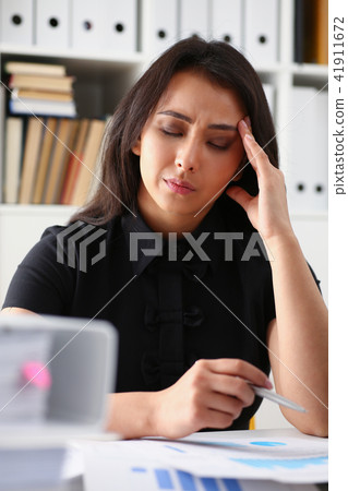 Tired and exhausted woman looks at documents propping up her head with her hands Tired and exhausted woman looks at documents propping up her head with her hands 41911672