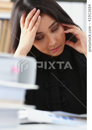 Tired and exhausted woman looks at documents propping up her head with her hands Tired and exhausted woman looks at documents propping up her head with her hands 41911684