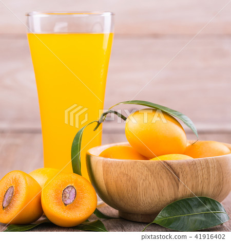 Fresh yellow marian plum fruit (Mayongchid in Thai name) and juice in glass on wooden table 41916402