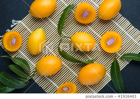 Fresh yellow marian plum fruit (Mayongchid) in Thai name) on black stone. Top view 41916481