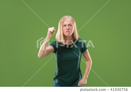 Portrait of an angry woman looking at camera isolated on a green background 41930756