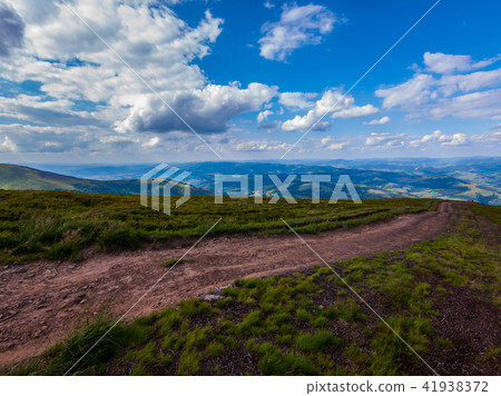A dirt road in the middle of a blue sky with white A dirt road in the middle of a blue sky with white 41938372