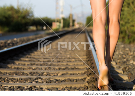 An attractive young woman with long brown hair walking near the railway An attractive young woman with long brown hair walking near the railway 41939166