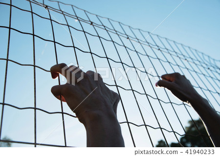 man climbing up a metal fence man climbing up a metal fence 41940233