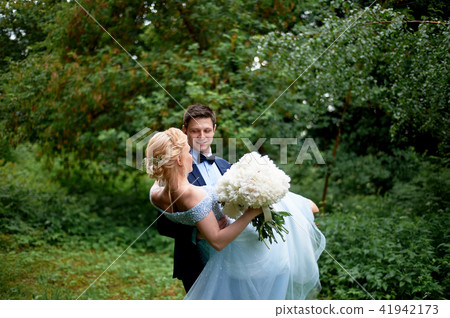 The groom circling the bride in his hands in a picturesque Park.She's in a blue embroidered dress 41942173