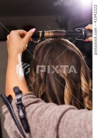hairdresser making a hair curling to a client hairdresser making a hair curling to a client 41942222