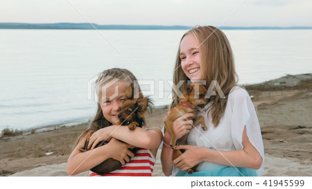 Two children playing which dogs on the sand on the beach. 41945599
