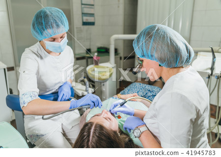 Woman at dentist clinic gets dental treatment to fill a cavity in a tooth. Dental restoration and Woman at dentist clinic gets dental treatment to fill a cavity in a tooth. Dental restoration and 41945783