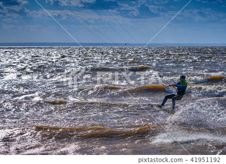 A male kiteboarder rides on a board on large river A male kiteboarder rides on a board on large river 41951192