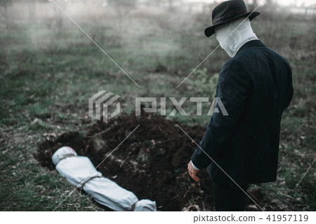 Bloody murderer stands against a grave with victim 41957119