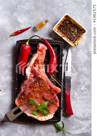 Raw steaks and frying pans with seasoning, garnishes and ingredients on a dark rustic background 41962575