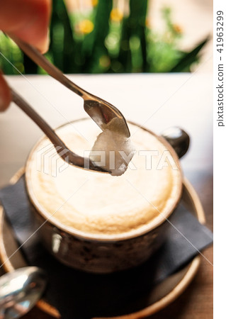 Add Sugar In Cup of hot latte coffee on wooden table 41963299