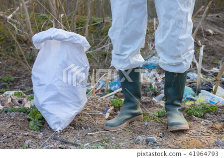 Volunteer man in white protective clothing collects garbage Volunteer man in white protective clothing collects garbage 41964793