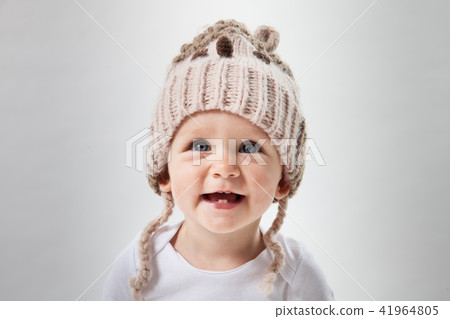 Portrait of a cute baby girl in a huge brown knitted hat. Isolated on white background. Portrait of a cute baby girl in a huge brown knitted hat. Isolated on white background. 41964805
