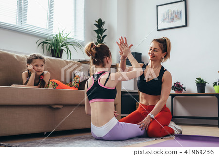 Young female athlete working out with a coach doing crunches giving high-five 41969236