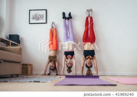 Females doing handstand pose near wall. Mother and daughters exercising at home, sport, family Females doing handstand pose near wall. Mother and daughters exercising at home, sport, family 41969240