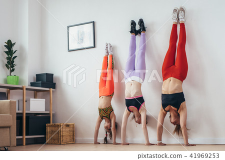 Females doing handstand pose near wall. Mother and daughters exercising at home, sport, family 41969253