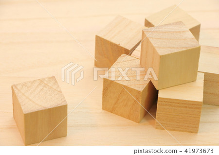 A cube wood placed on a wooden board. 41973673