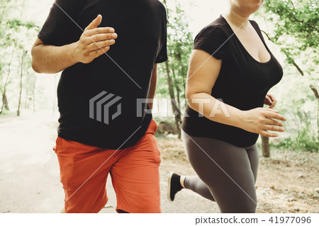 Overweight couple losing weight running together Overweight couple losing weight running together 41977096