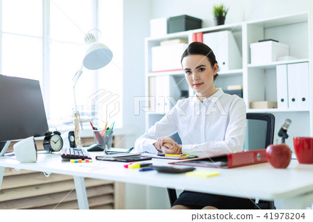 A young girl is sitting at the computer desk in the office. 41978204