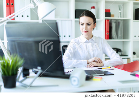 A young girl is sitting at the computer desk in the office. 41978205