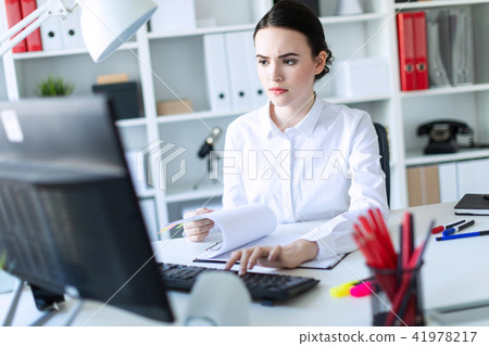 Young girl in the office working with documents at the computer. Young girl in the office working with documents at the computer. 41978217