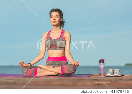 Sporty young girl in the morning on seashore, practicing yoga. Woman do gymnastics outdoor. Health 41979756