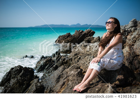 Young woman in dress sits on the rock on the coast of the ocean 41981623