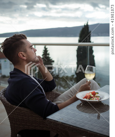 Pensive young man with glass of white wine Pensive young man with glass of white wine 41981873
