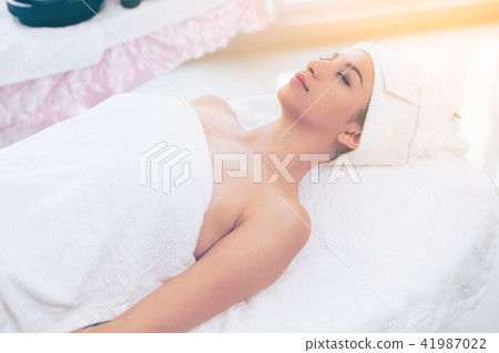 Relaxed young woman lying on spa bed for massage. Relaxed young woman lying on spa bed for massage. 41987022