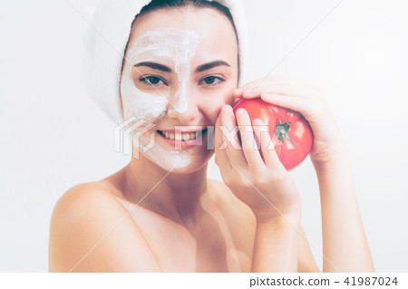 Woman get facial mask with tomato cream extract. Woman get facial mask with tomato cream extract. 41987024