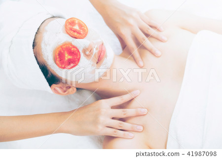 Woman get facial mask with tomato cream extract. 41987098