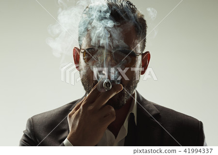 The barded man in a suit holding cigar 41994337