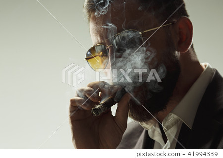 The barded man in a suit holding cigar The barded man in a suit holding cigar 41994339