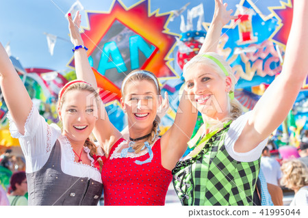 Friends visiting Bavarian fair having fun at carousel  41995044