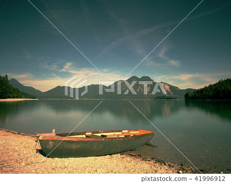 Boat anchored on bank of lake. Mountains in water Boat anchored on bank of lake. Mountains in water 41996912