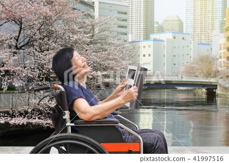 Senior woman laughing while read magazine in park Senior woman laughing while read magazine in park 41997516